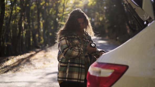 Happy Woman Opens Trunk of White Car Takes Map and Thermocup