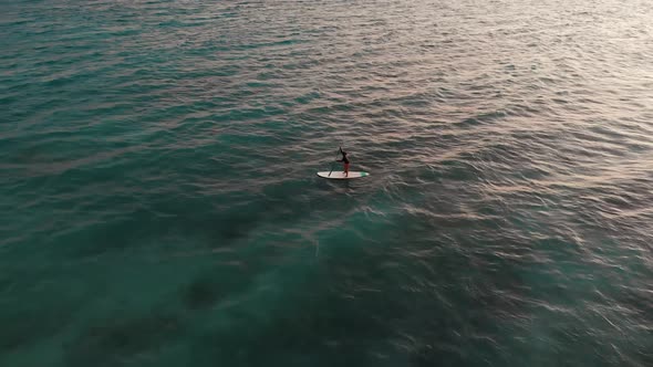 Aerial Shot of Man Practicing Paddle Board at Sunset on Stunning Place