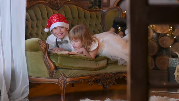 Funny children lefat on the couch read a book and play. alt