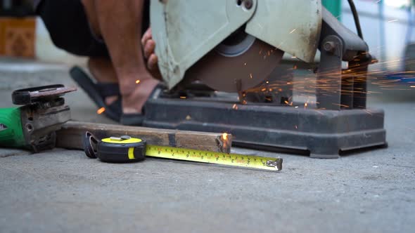 Close up a construction worker cuts off metal fittings with a grinder.