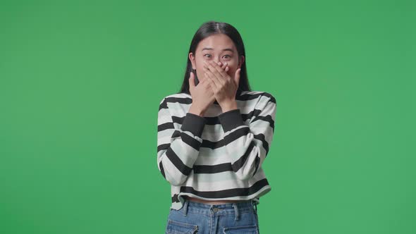 Asian Woman Surprised While Standing In Front Of Green Screen Background alt