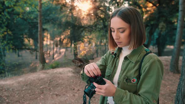 Girl rewinding analog camera film in the forest. Medium shot, fixed shot. alt