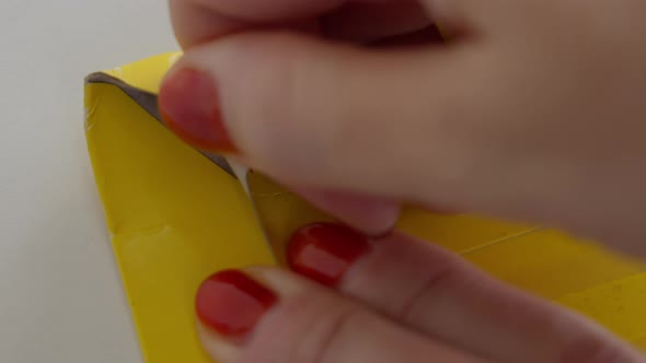 Women's Hands with a Red Manicure Open a Yellow Postal Envelope Opening a Special Ribbon alt