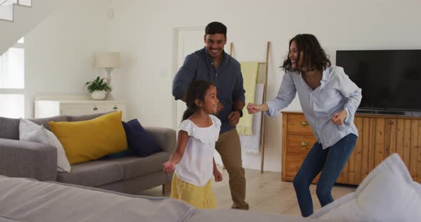 Happy hispanic family with daughter dancing having fun in living room alt