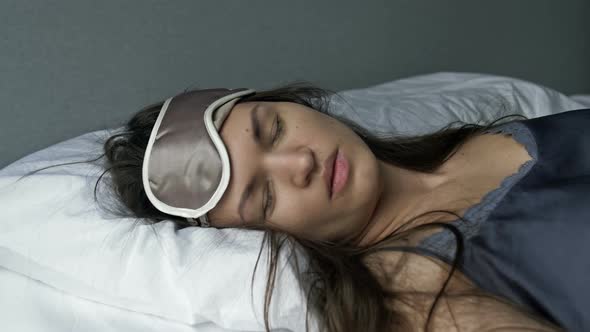 Tired Woman Falls Onto the Bed Puts on a Sleep Mask and Instantly Falls Asleep alt
