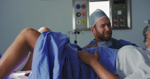 Side view of Caucasian female surgeon examining pregnant woman during labor in operation theater at alt