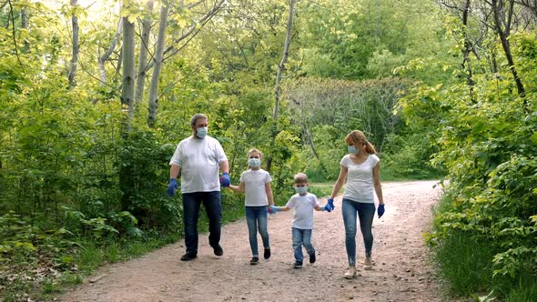 Father, mother, son and  daughter  walk in the Park in medical masks