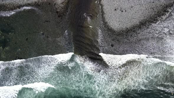 Cinematic top-down view of waves rolling ashore at Sombrio beach on Vancouver Island. 4k aerial foot alt