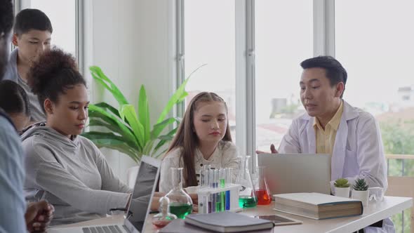 Teacher teaching and explaining chemistry experiment in science classroom alt