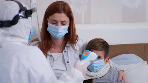 Female Healthcare Professional Are in Protective Suit Examines Health of Male Child with Symptoms of