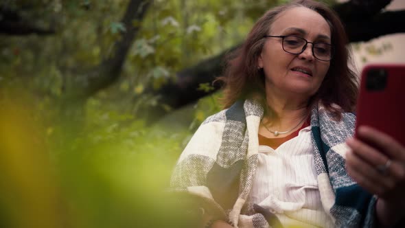 A Mature Adult Woman with Long Hair Taking a Video Call By Her Phone