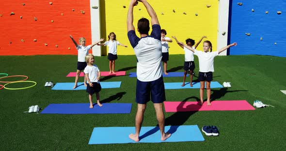 Yoga instructor instructing children in performing exercise alt