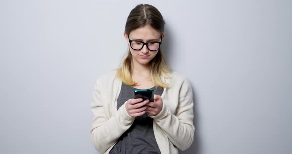 Teenager student girl with glasses uses a mobile phone