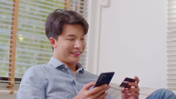 Asian handsome man using credit card for pay online shopping on computer laptop alt