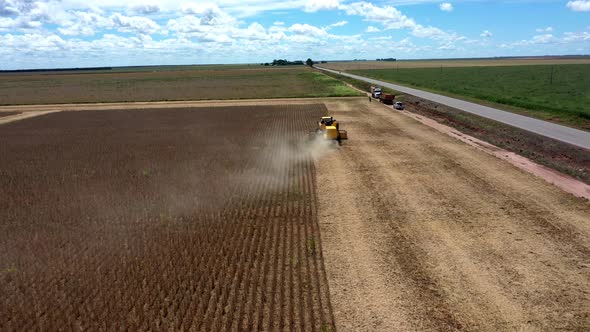 Combine harvester gathering soybeans from a field on land from deforested Brazilian Savannah - aeria alt