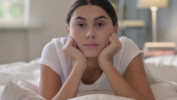 Latin Woman Laying in Bed Looking at Camera alt