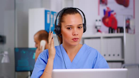 Doctor Assistant Using Headphones in Hospital Answering To Patients Calls alt