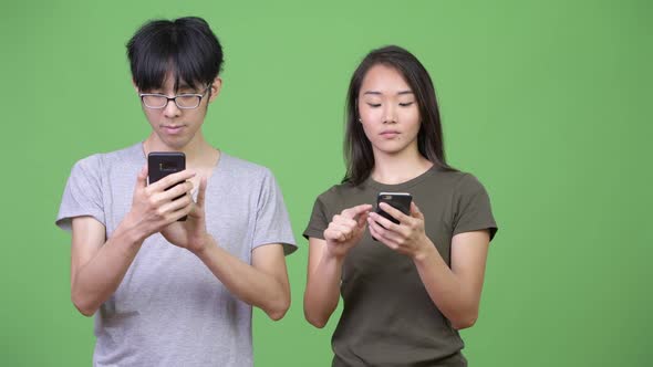 Young Asian Couple Using Phone Together