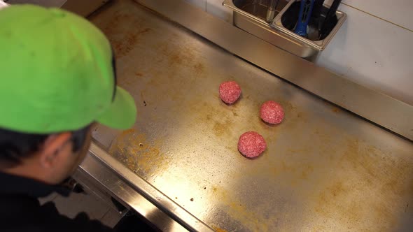 Professional Cook Preparing Raw Hamburger Meat on a Hot Plate in Commercial Restaurant alt
