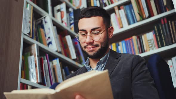 Man in eyeglasses reading book in book shop alt