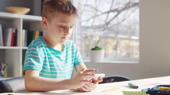 Boy is Doing  Homework at the Table. Cute Child is Learning at Home. alt