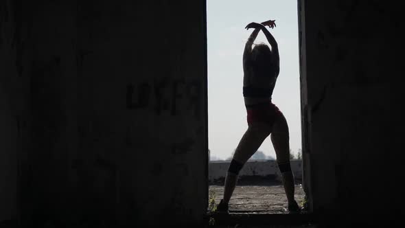 Girl Dances Twerk in the Doorway on the Roof of an Abandoned Building. Girl in Red Shorts and Tights