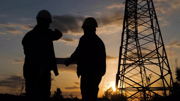 Silhouette of Engineers Looks at the Construction of High-voltage Power. Teams Engineer Looking alt