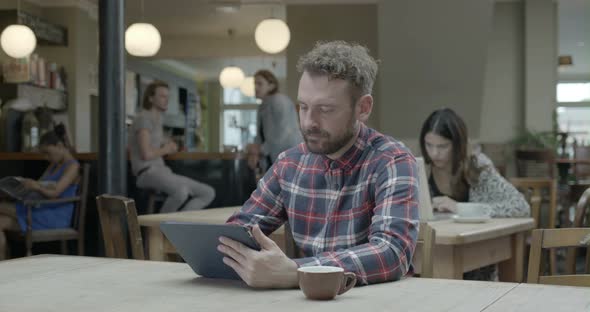 Man using tablet and drinking coffee in pub