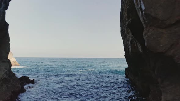 Blue Ocean Water in Gaztelugatxe, Spain with Stone Archway on a Sunny Day alt