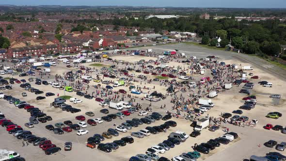Aerial pull away and rise up from a busy market and car boot sale in Hull, England UK alt
