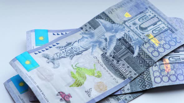 Man recalculates banknotes of Republic of Kazakhstan tenge, five, ten twenty thousand denominations. alt
