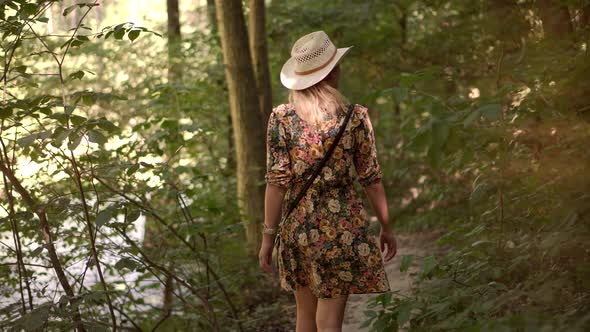 Relaxing Woman In Hat Walking Pine Forest. Holiday Vacation Tourist Journey Trip In Warm Day. alt