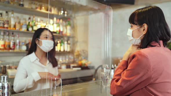 Woman customer receiving food from waitress with face mask on counter in restaurant during covid19. alt