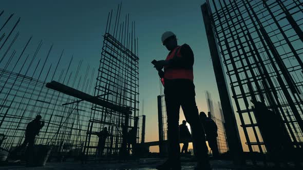 People Work on Construction Site on Sunset Background. alt