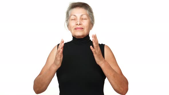 Happy Female Pensioner with Gray Tied Hair Meditating in Front of Camera Taking Deep Breaths alt