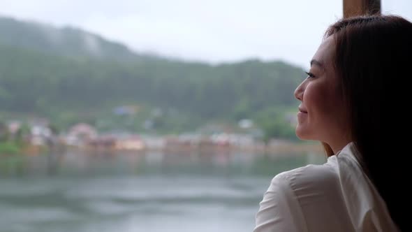 A beautiful young asian woman looking at the lake in mountains village