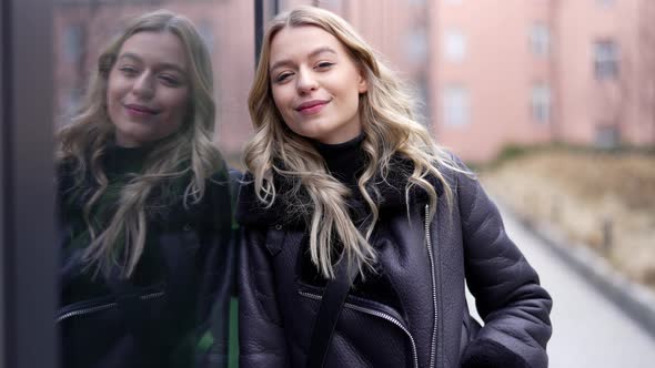 Happy Woman Leaning on Glass Wall alt
