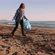 Girl volunteer picking up plastic bottles trash left on beach, keeping beach clean. - VideoHive Item for Sale