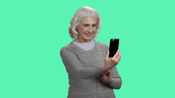 Mature Woman Taking Selfie on Color Background alt