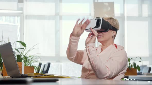 Mature Businesswoman Trying 3d Virtual Reality Glasses at Her Workplace alt