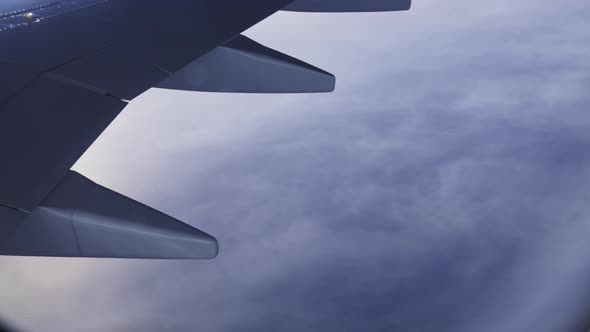 Closeup View Through Plane Window on Aircrafts Wing and White Cloud Underneath alt