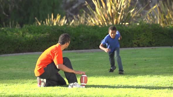 A father teaching his sons how to play American football. alt