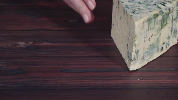 Large wedge of blue cheese on a dark wooden background. alt