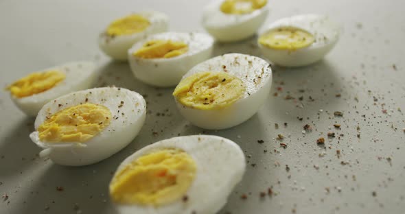 Video of close up of peppered halves of hard boiled eggs on grey background alt