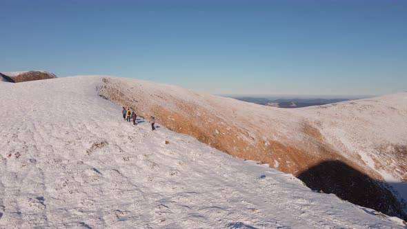 Four Climbers Walk on the Ridge of a Snowy Mountain