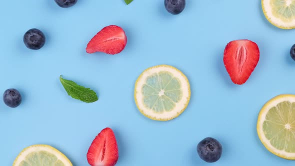 A Rotating Background of Blueberries Strawberries Lemon Slices and Mint Leaves on a Blue Background