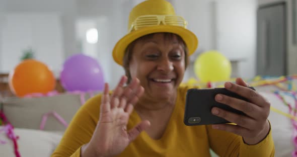 Happy african american senior woman making new year's eve smartphone video call blowing kisses alt