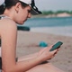 Young Woman Uses a Smartphone on the Beach - VideoHive Item for Sale