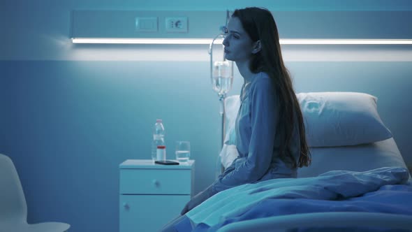 Young patient sitting on a hospital bed at night and feeling sad