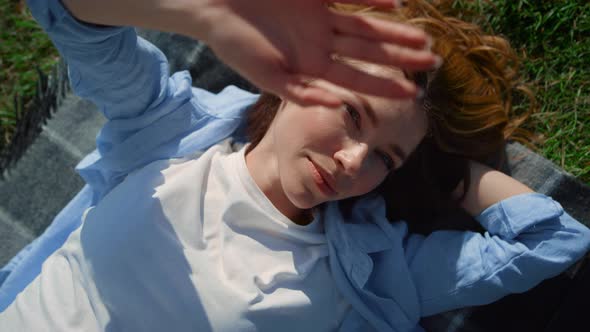 Portrait of Playful Woman Covering Face From Bright Sun Beams in Spring Meadow alt
